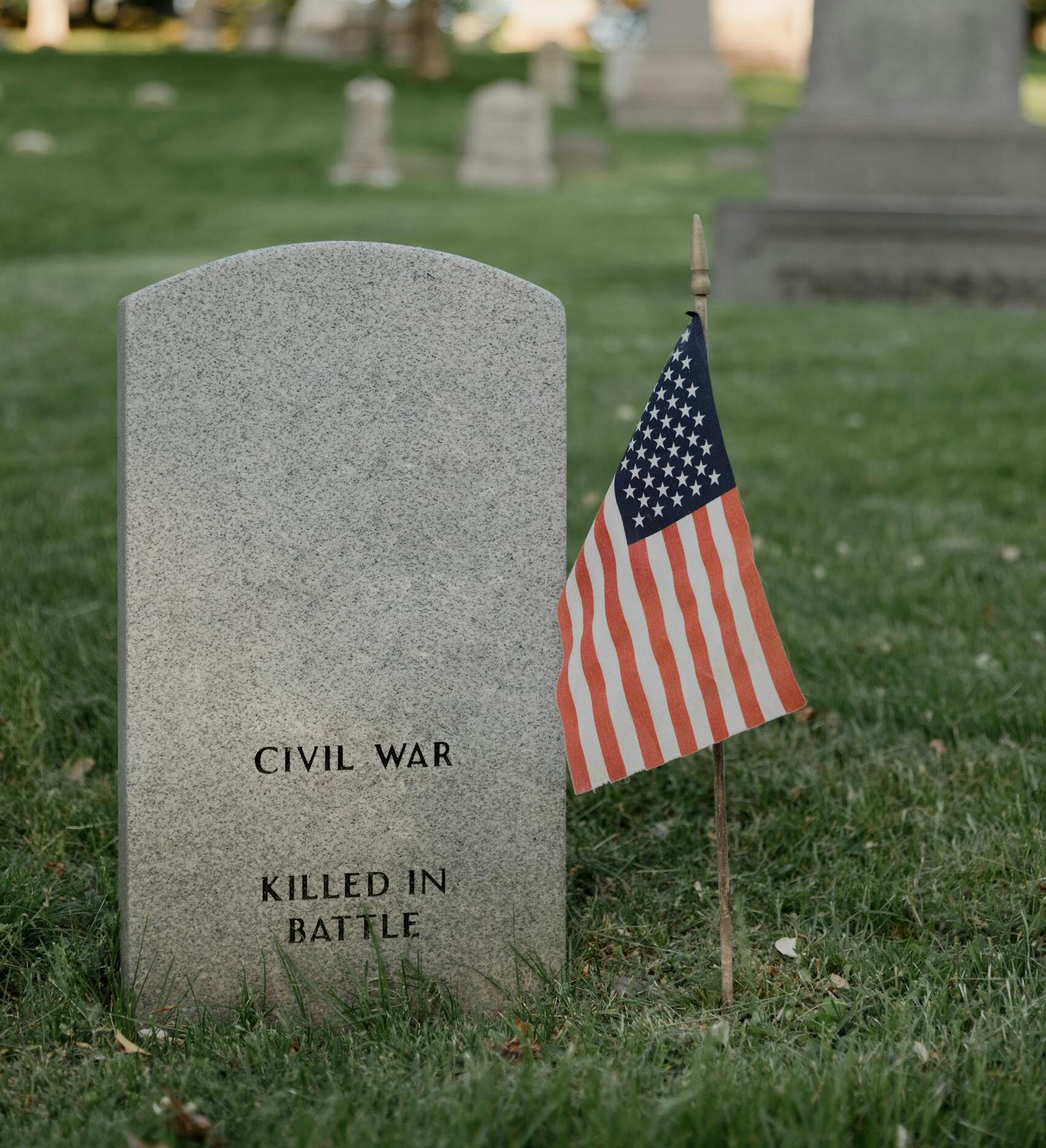 Civil War grave with American flag in a serene cemetery setting.